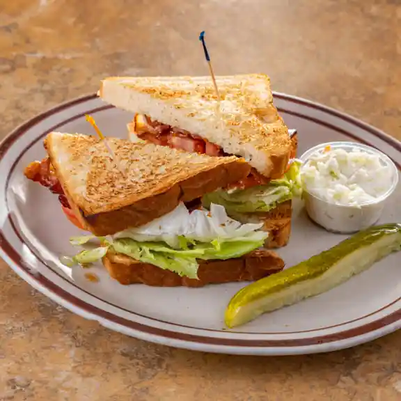 Grilled panini sandwich served with cream cheese and a pickle