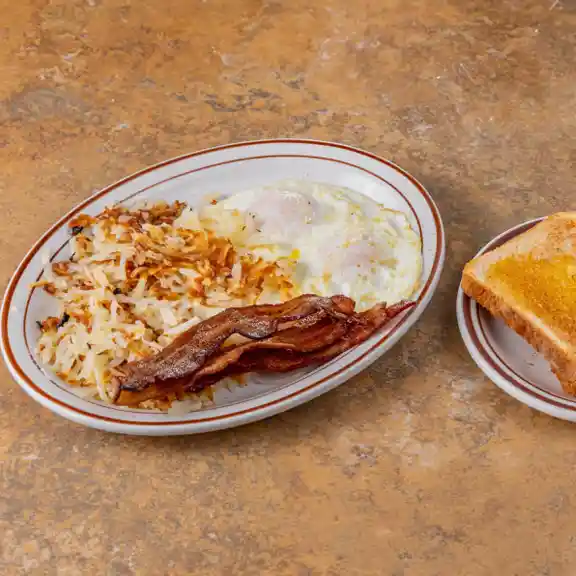 Breakfast plate with hash browns, bacon, fried eggs, and buttered toast