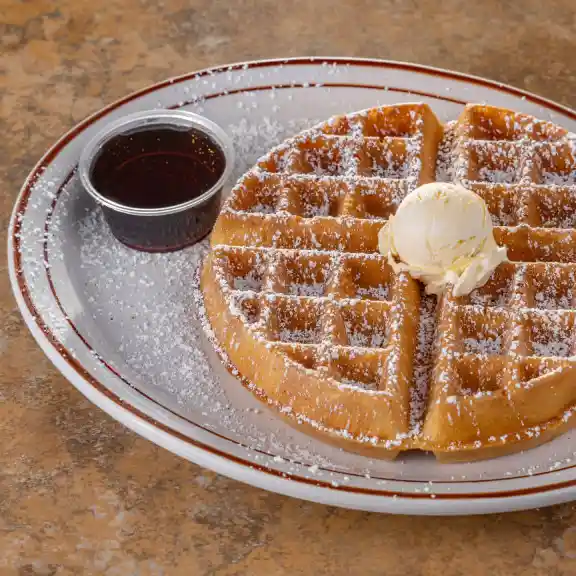 Golden Belgian waffle topped with butter, syrup, and powdered sugar